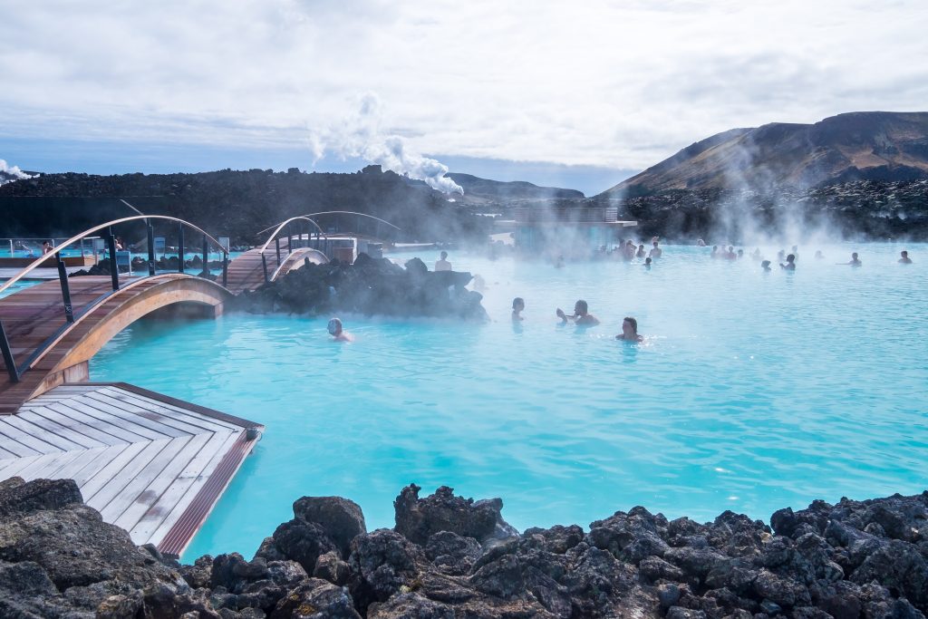 blue lagoon in iceland with wooden bridges leading over it