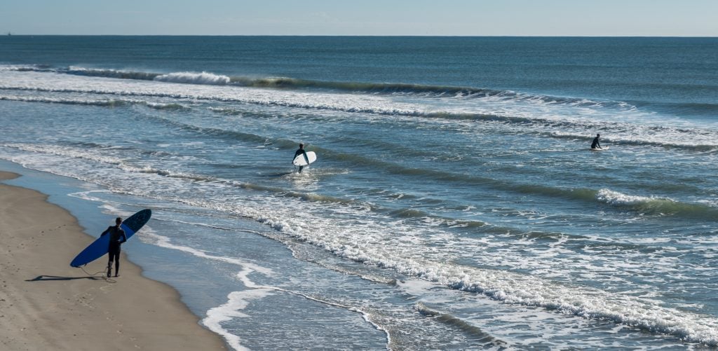 surfers entering the water one of the top things to do emerald isle north carolina