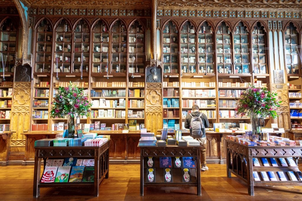 downstairs bookshelves with tables in famous bookstore porto portugal