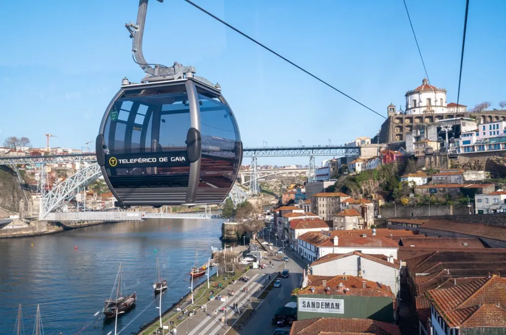 view of cable car in front of bridge and monastery, a must during a one day in porto itinerary