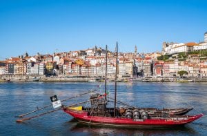 traditional wooden boat in porto with cityscape in the background, a must see on a one day in porto itinerary