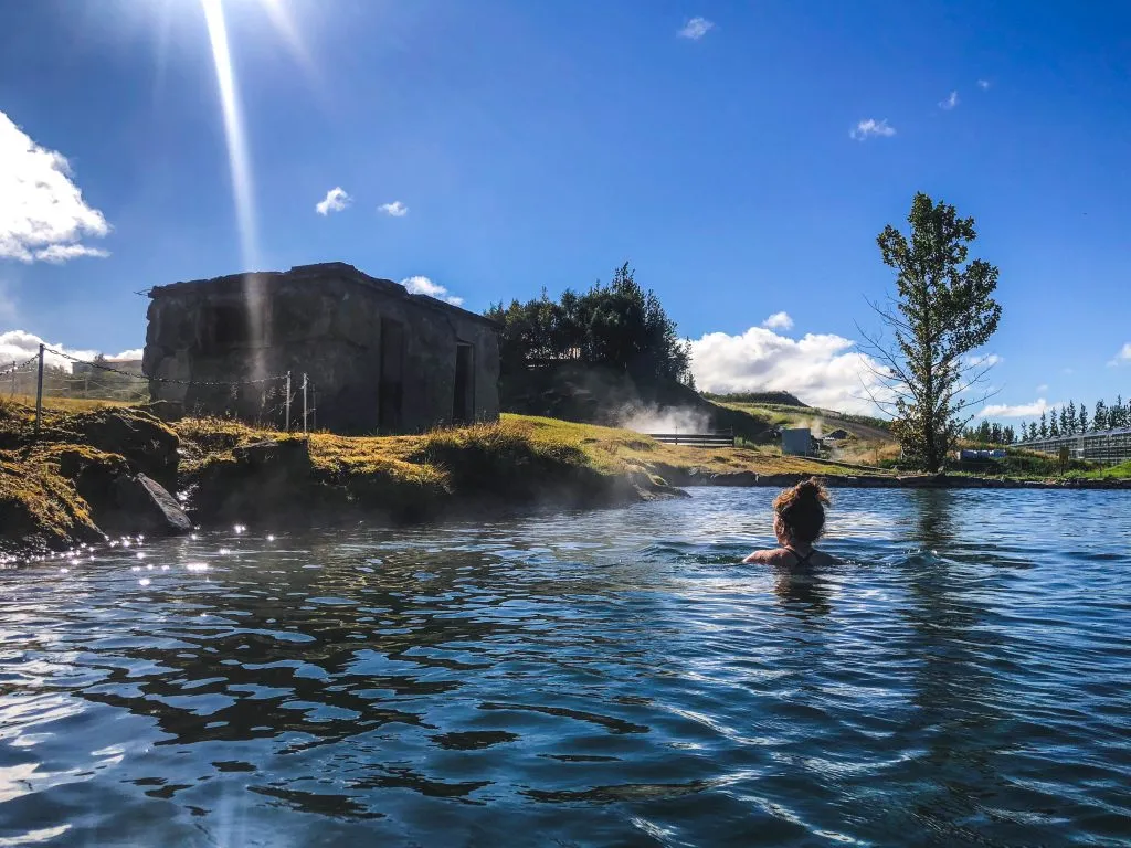 person soaking in iceland secret lagoon on a sunny day, one of the best activities iceland