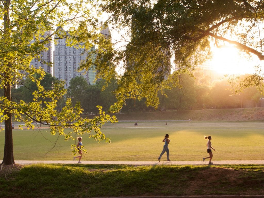 people walking through piedmont park at sunset in atlanta on the weekend
