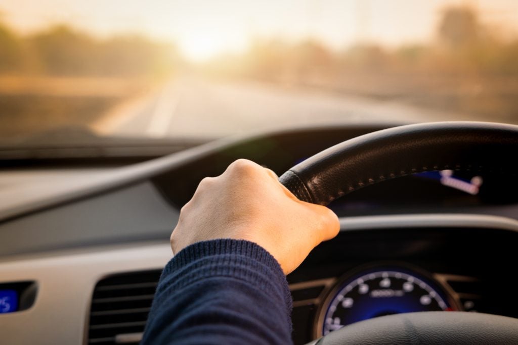 person's hand on the wheel driving a car