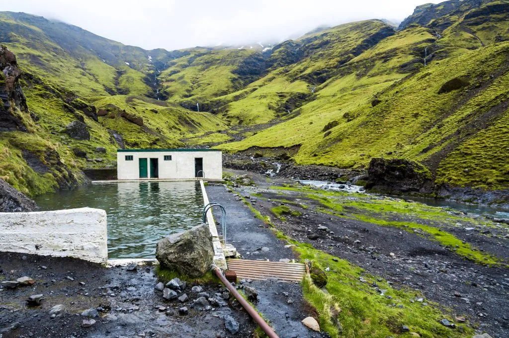 Seljavallalaug hot spring in iceland with small hut in the background, one of the best things to do in iceland