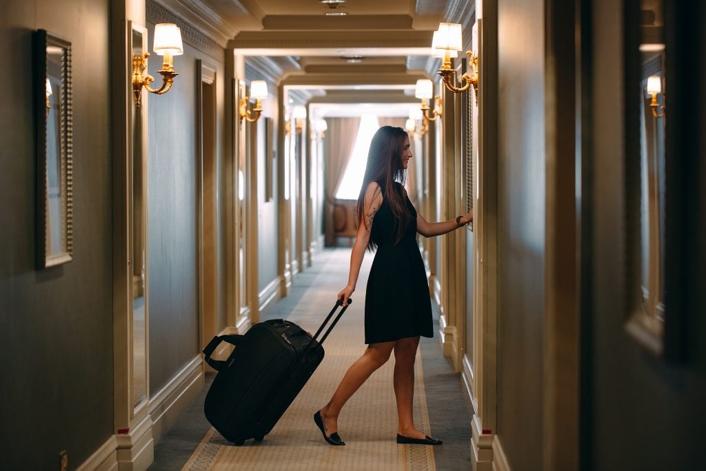 woman with a suitcase walking through a hotel hallway