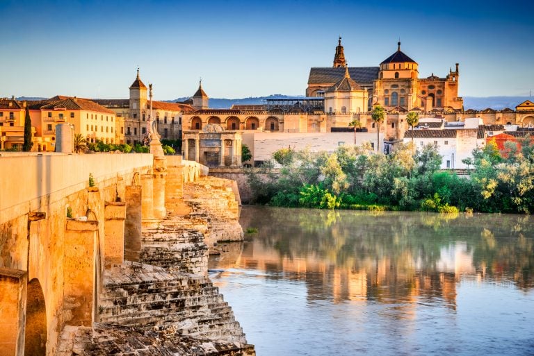 view of roman bridge and cathedral in cordoba, some of the best things to do in cordoba spain