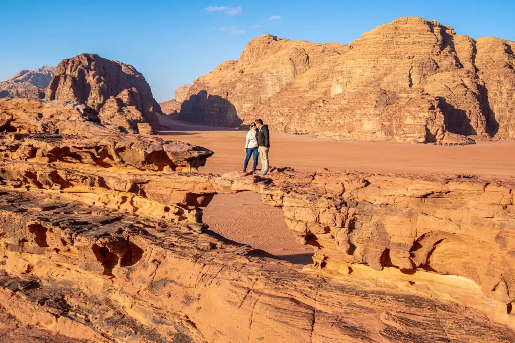 kate storm and jeremy storm standing on an arch when visiting wadi rum jordan