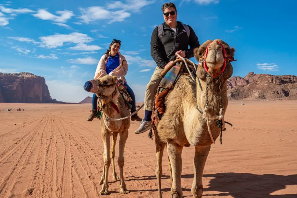 kate storm and jeremy storm riding camels when camping in wadi rum jordan