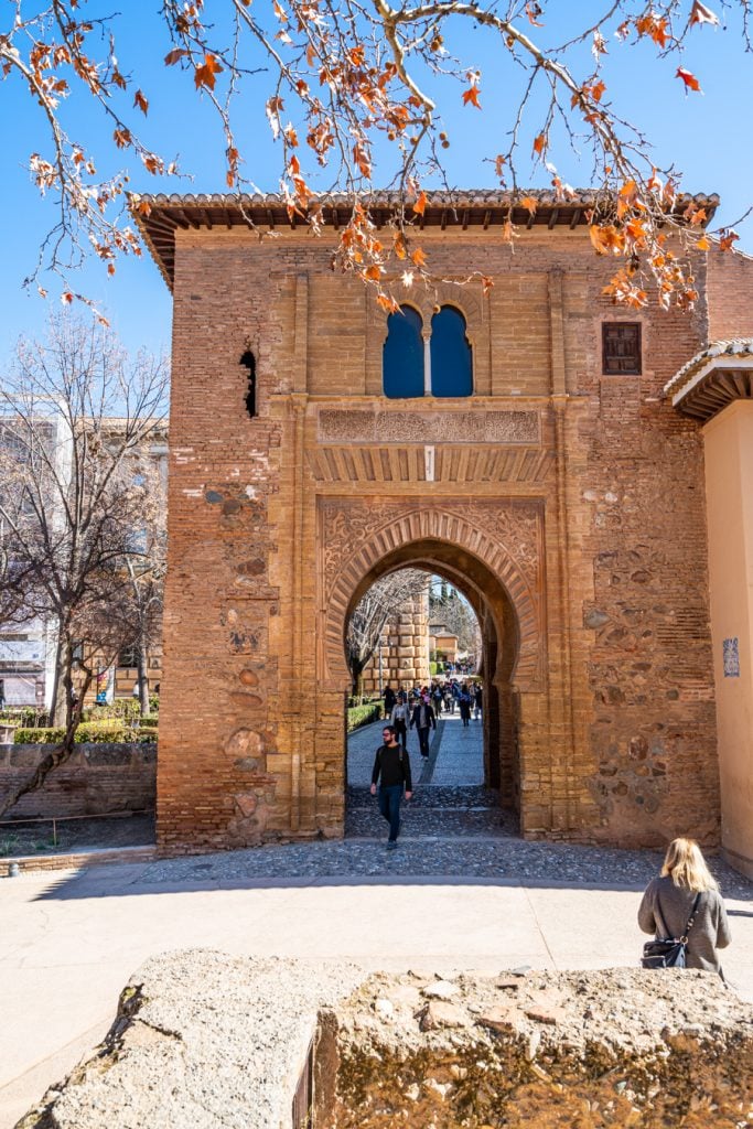 alhambra gate with branches of a tree in the foreground