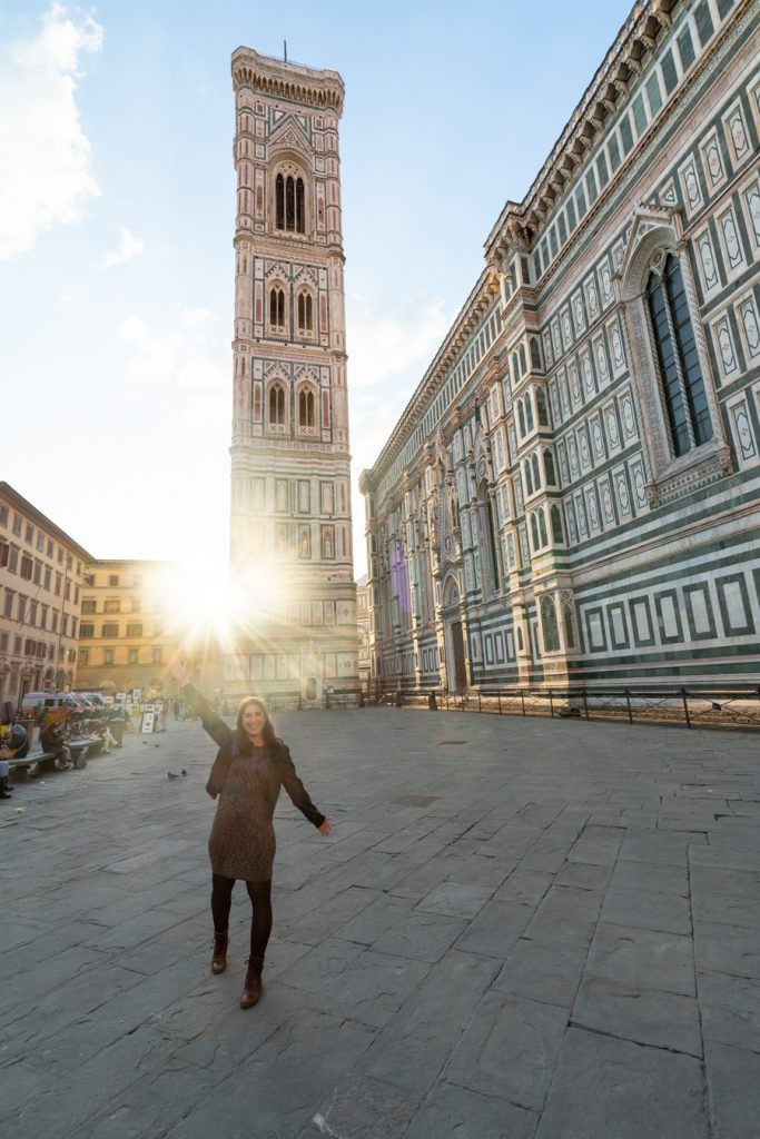 kate storm standing in front of giottos bell tower with a sun flare