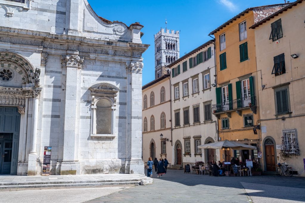 small street in lucca italy with white church to the left