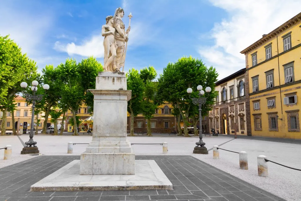 white statue in piazza napoleone in lucca italy with trees in the distance