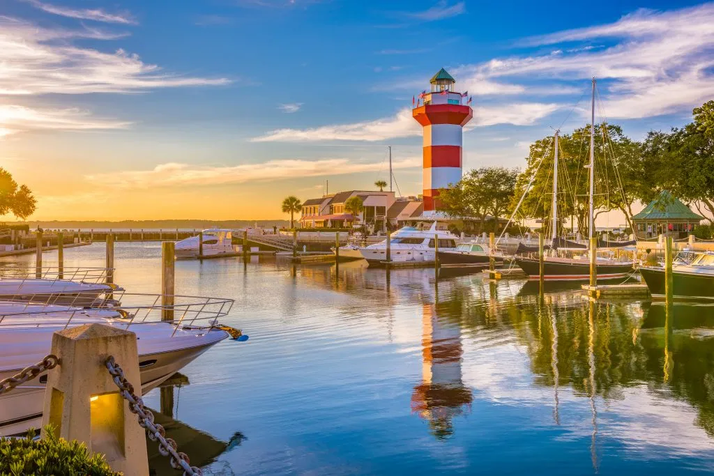 red and white lighthouse and small harbor in hilton head sc, one of the best stops on a deep south usa road trip route