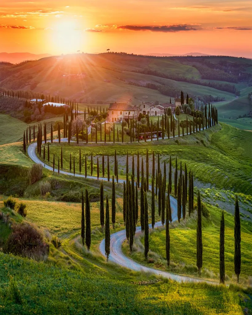 sunset over the val d orcia tuscany italy with a winding path of cypress trees