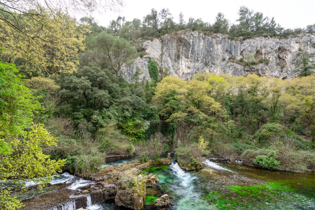 photo of flowing river and karst cliffs in fontaine-de-vaucluse, one of the best places to visit in south of france