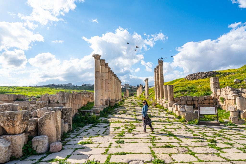 kate storm standing along roman road in jerash, one of the best places to visit jordan road trip