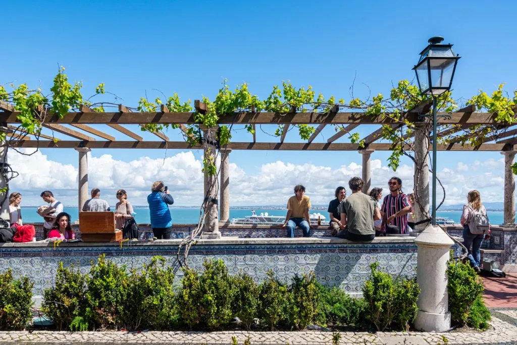 view of crowd overlooking lisbon at a miradouro da santa luzia