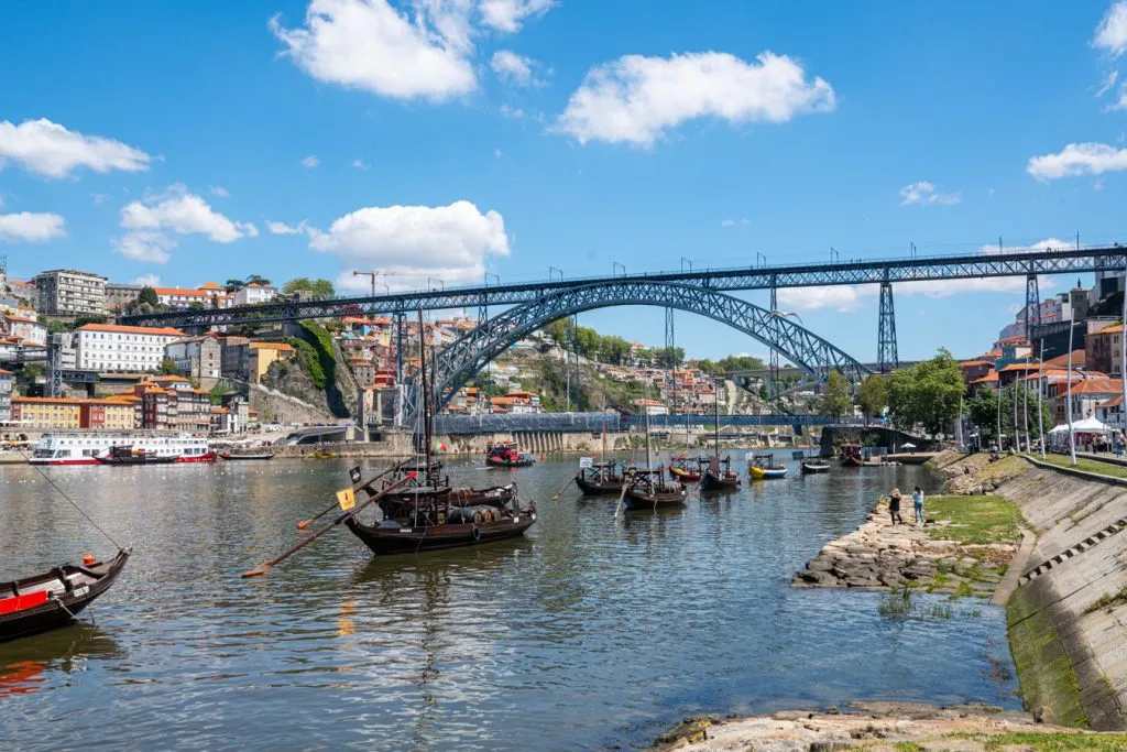 historic boats on tagus river in porto portuagal with bridge behind them