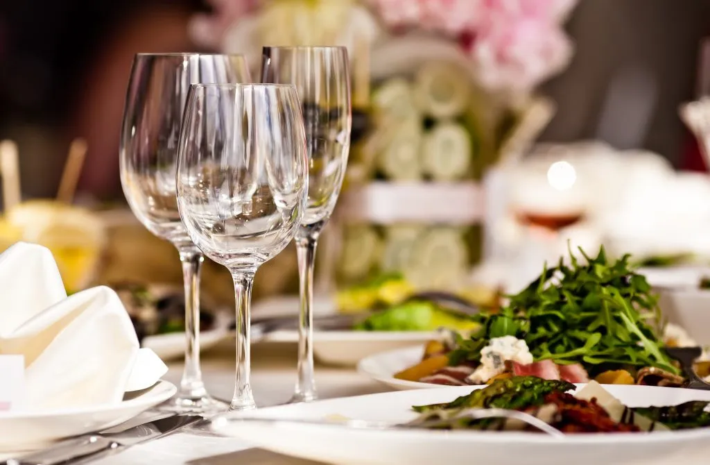 restaurant meal on white plates with several wine glasses on the table
