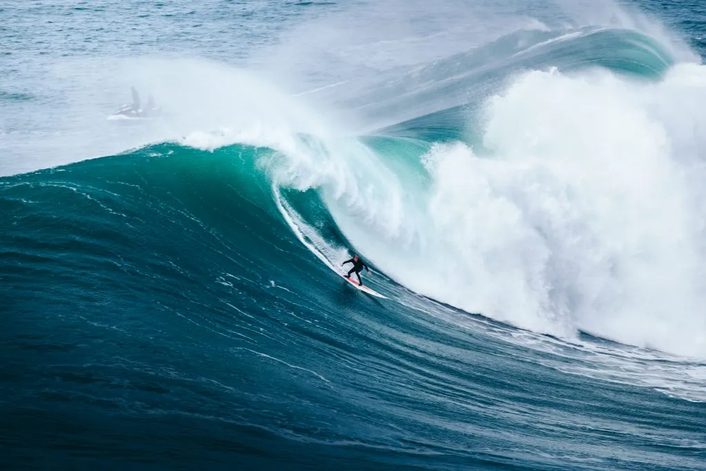 surfer riding a giant wave in nazare as seen on a portugal road trip itinerary