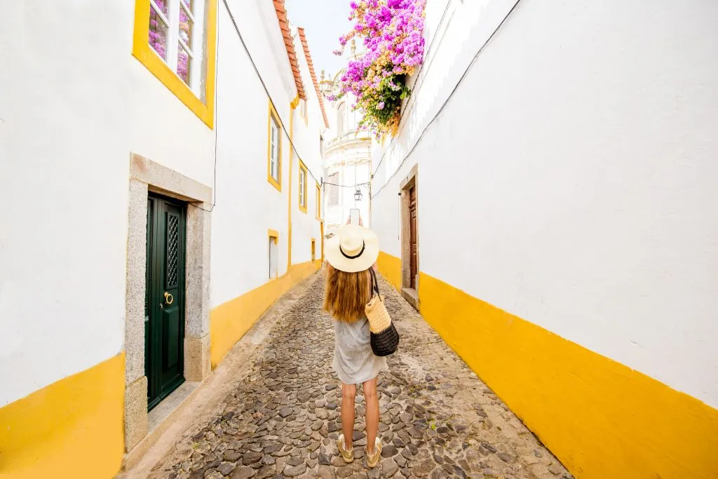 young woman on a whitewashed street in evora portugal