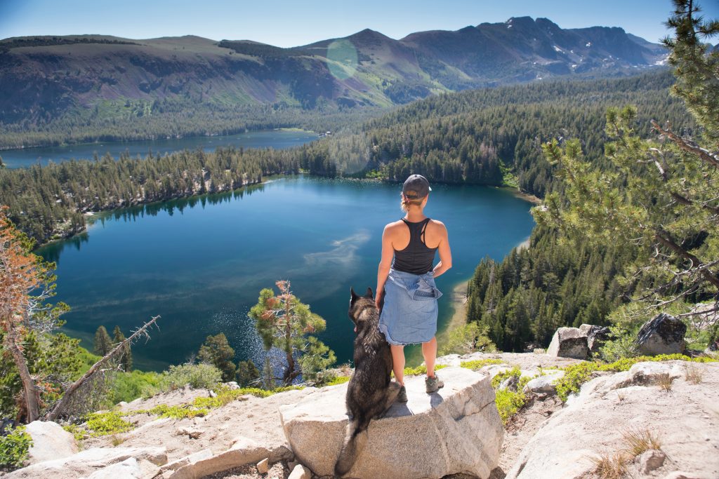 woman standing with her dog overlooking a lake when hiking in beautiful mammoth lakes ca vacation destinations