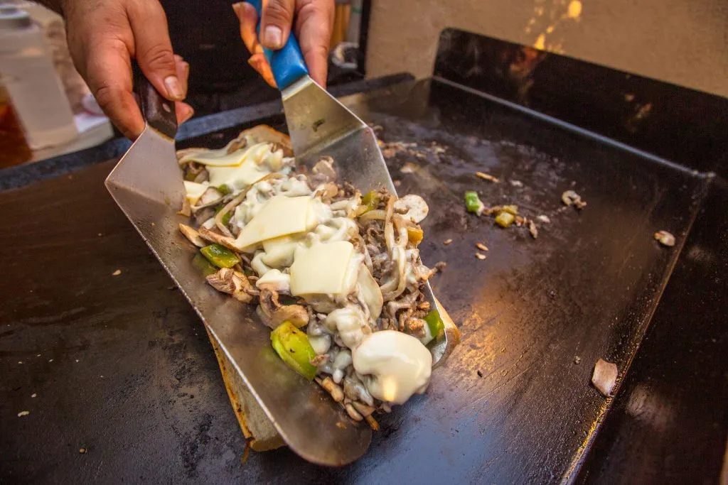 philly cheesesteak being made on a grill