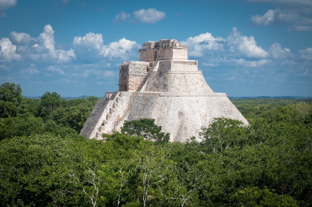 temple of the magician at uxmal mayan ruins in mexico peeking above the tree line