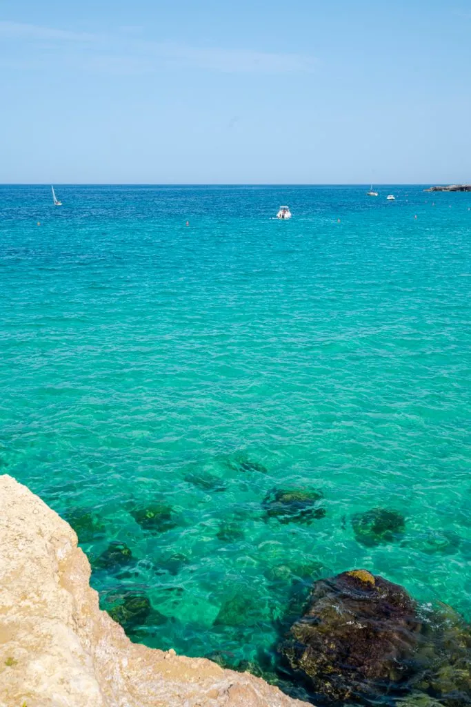 turquoise water in monopoli italy with sailboats in the distance