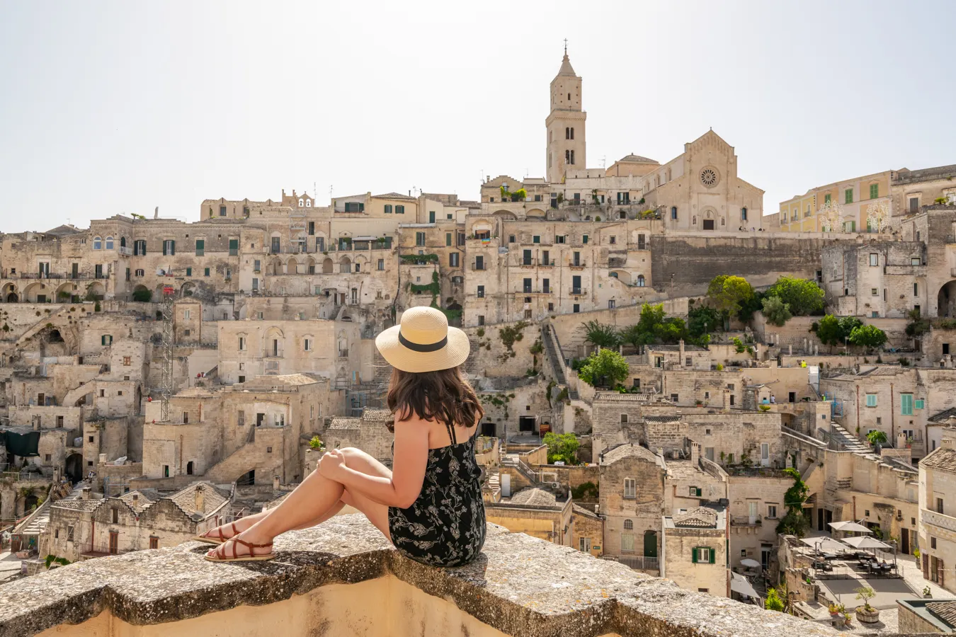 kate storm sitting on a ledge overlooking matera, one of the top destinations in southern italy vs northern italy