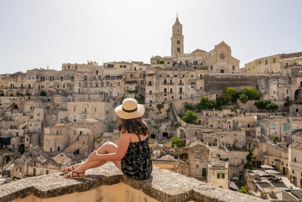 kate storm sitting on the edge of a balcony on matera in summer--visiting matera in july can be considered a bit of an italy travel mistake