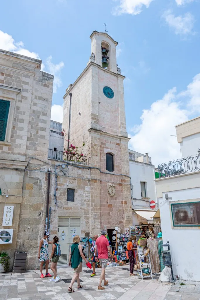 clock tower in otranto puglia with people walking in front of it