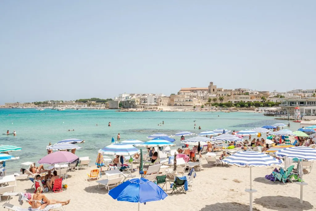 colorful umbrellas in the foreground with water of otranto italy in the background