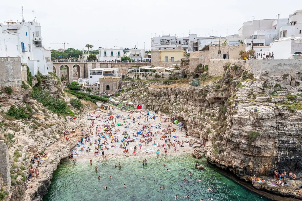 crowded beach in polignano a mare as seen from above during june in italy