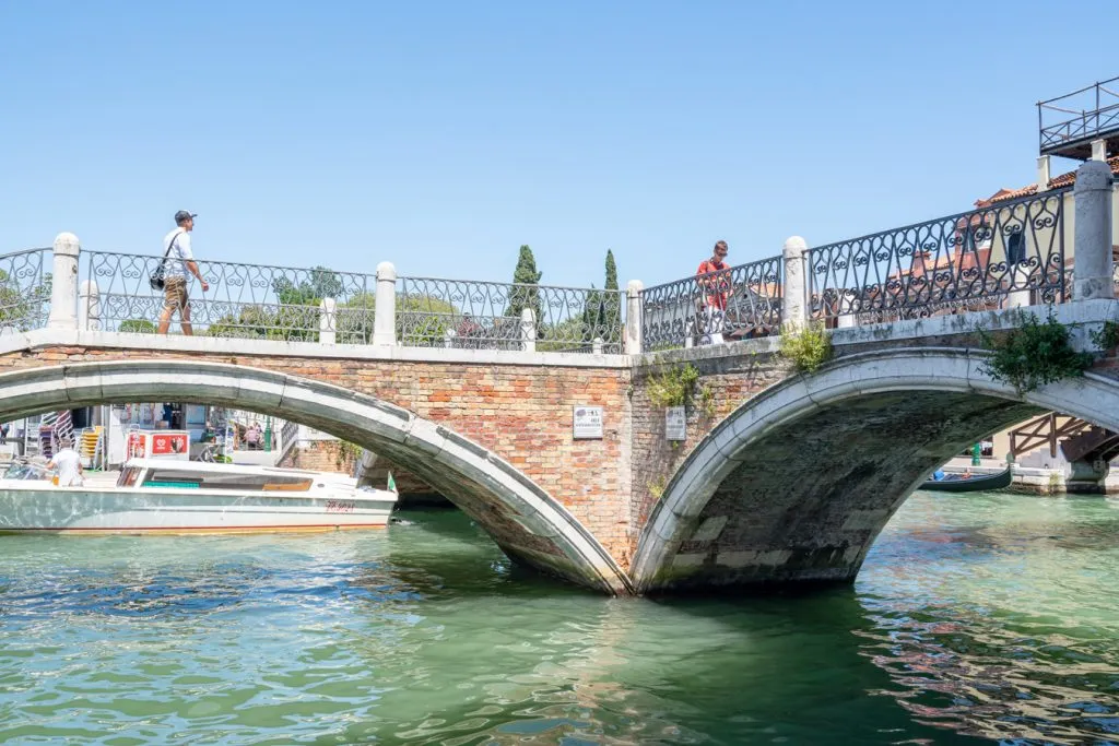 part of the ponte tre ponti as seen from the side with canal in the foreground