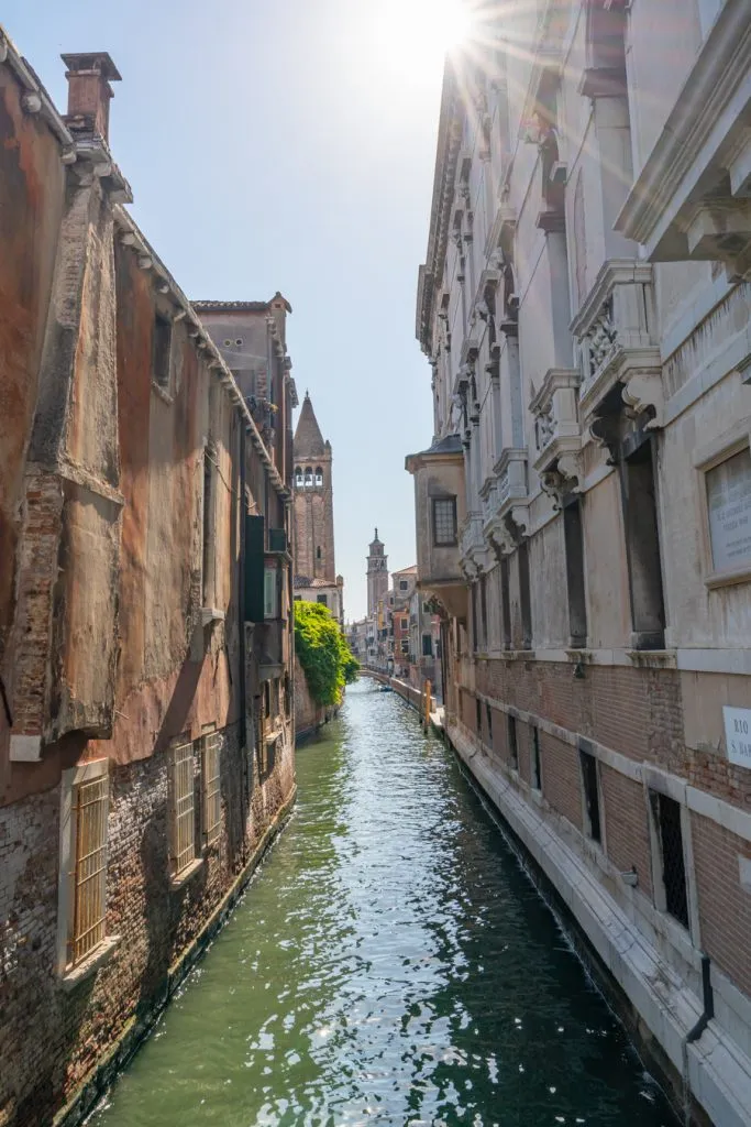 view of a small canal in dorsoduro venice with sun flare at the top of the image