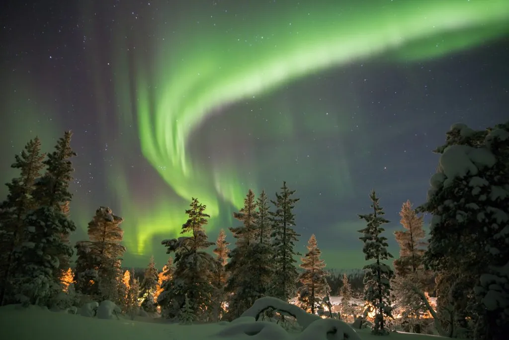 northern lights above the trees in abisko, one of the best places in europe in winter