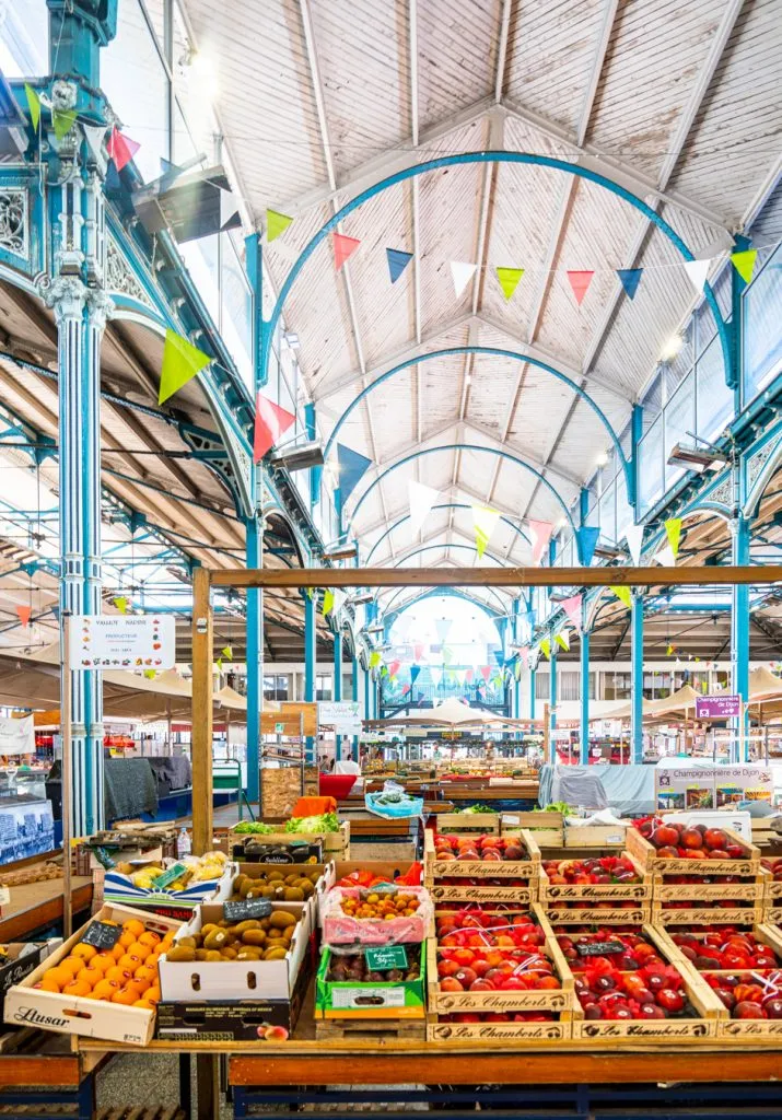 interior of les halles food market with fruit stand in the foreground, one of the best places to visit in dijon france