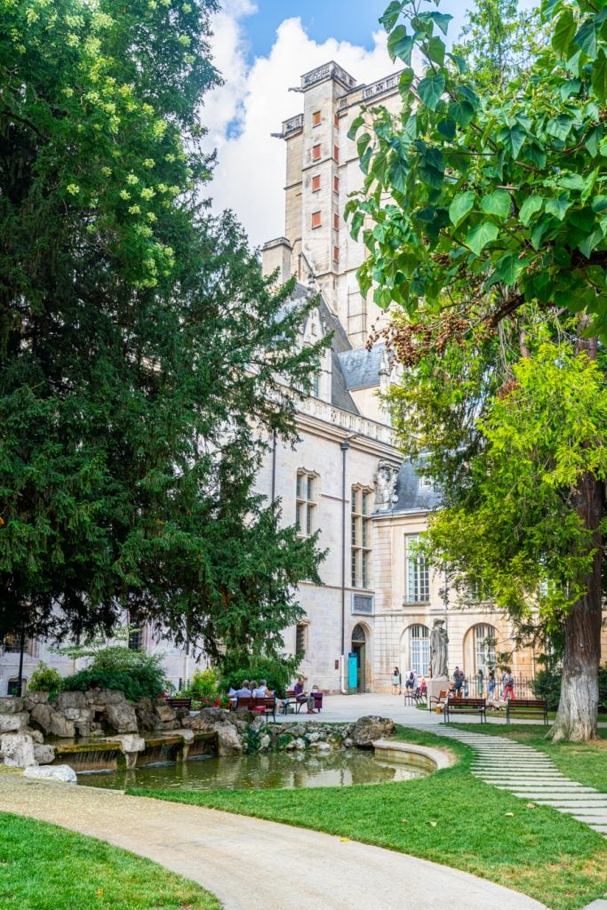 view of the dijon ducal palace from behind with trees in the foreground
