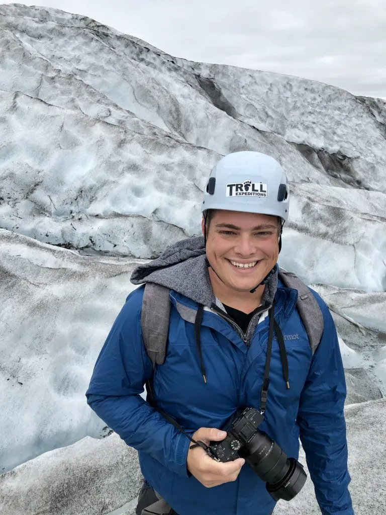 jeremy storm holding a camera and smiling on an iceland glacier walk