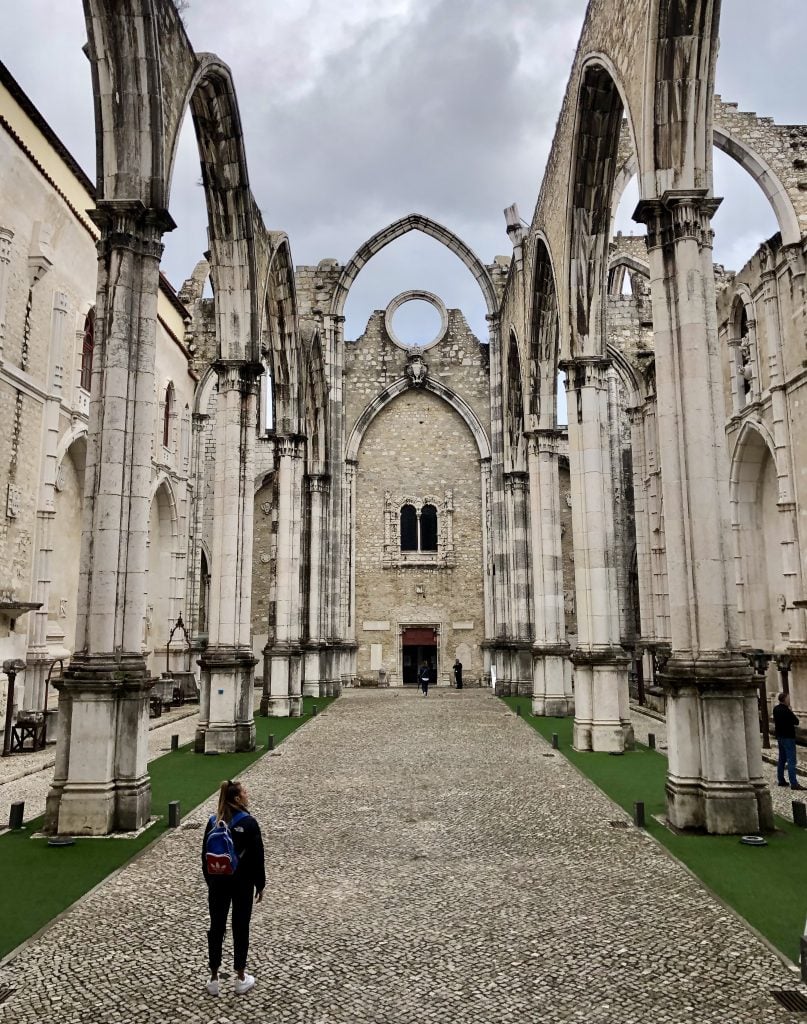 woman standing inside the carmo convent in a cloudy day during a winter trip to lisbon portugal