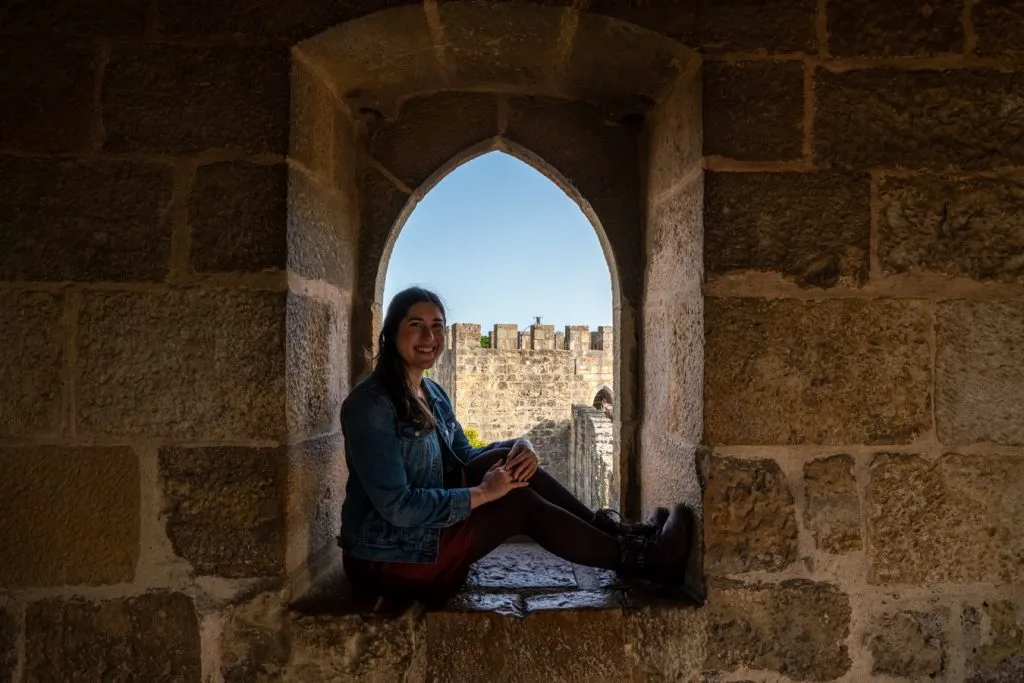 kate storm sitting inside a small room in sao jorge castle, one of the best things to do in lisbon portugal