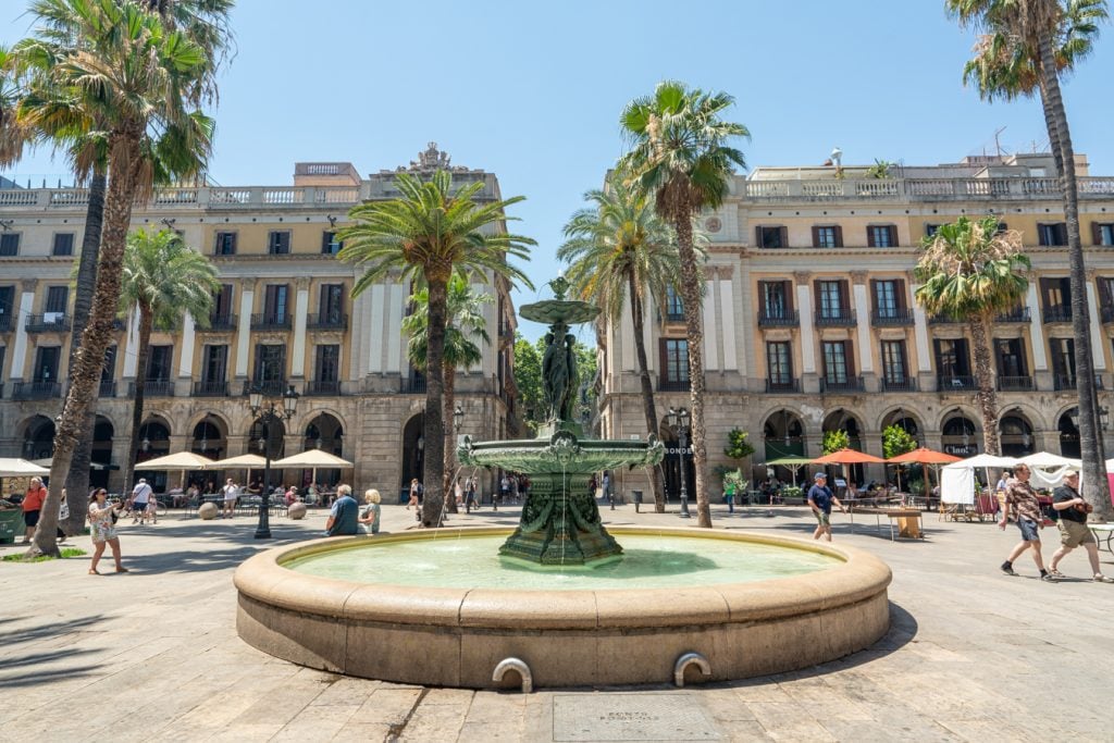 plaza catalunya in barcelona spain with a fountain surrounded by palm trees