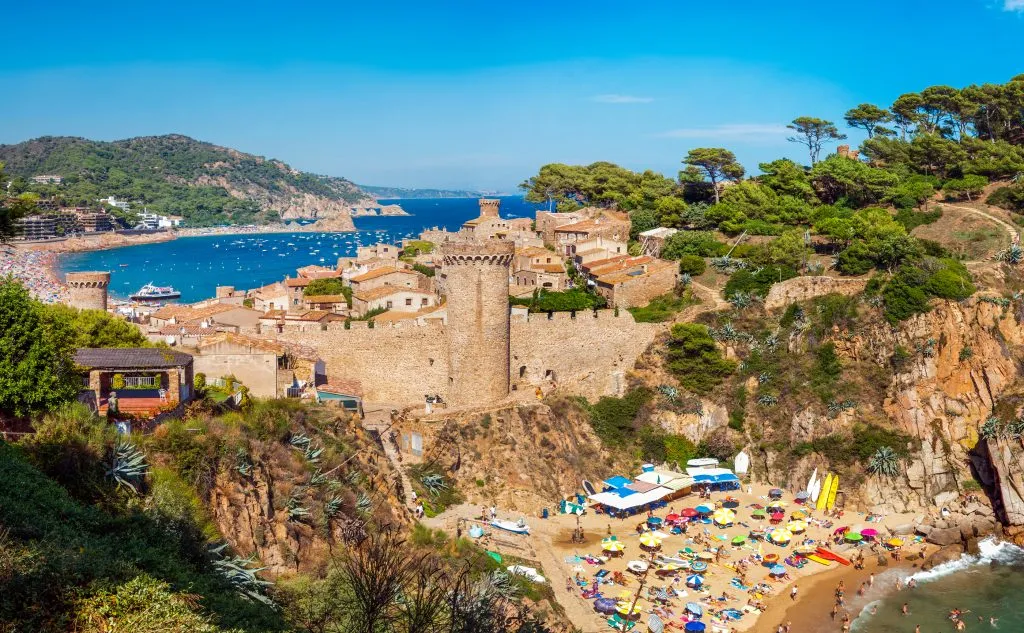 tossa de mar with beach in the foreground and castle in the background, one of the most beautiful seaside towns in spain