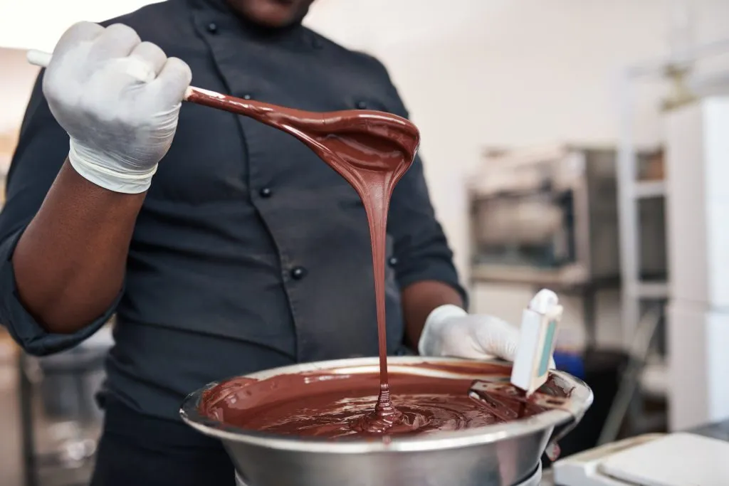 =man stirring stainless steel bowl of melted chocolate