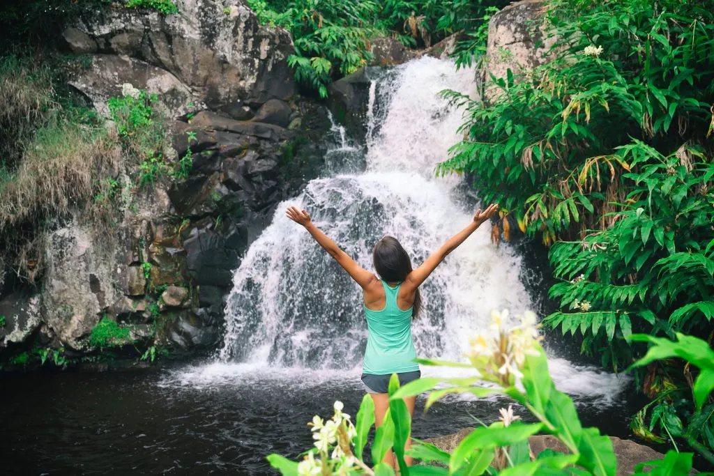 woman in a green tank top standing in front of waimea falls, one of the best places to visit oahu hawaii