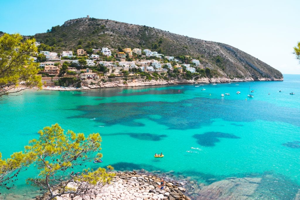 view of moraira spain with whitewashed town in the distance and sea in the foreground