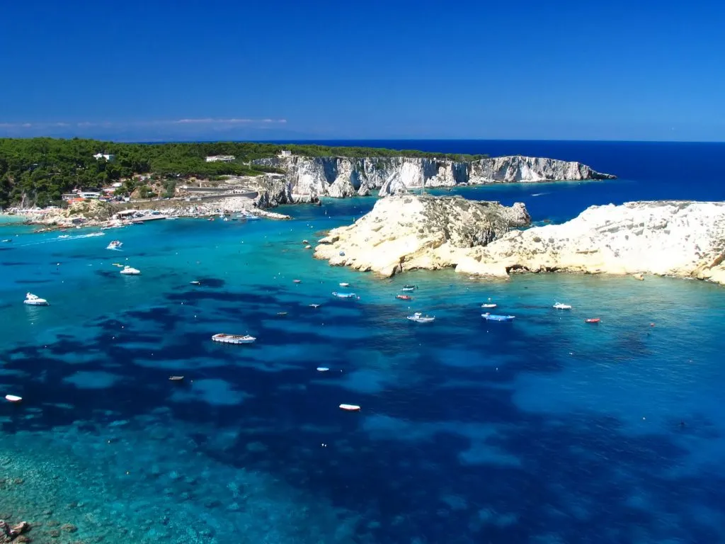 view of white cliffs, bright blue water and sailboats from above on tremiti islands