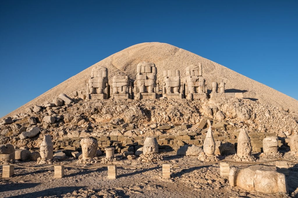 antique statues with mount nemrut in the background, one of the most interesting things to see in turkey